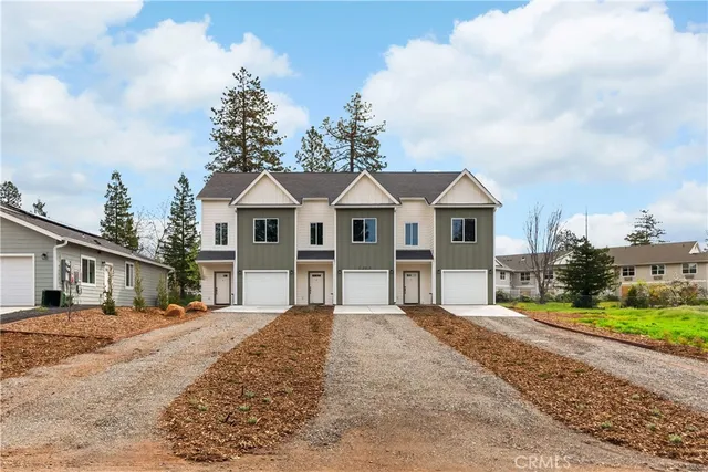 a view of a white house next to a yard with large trees