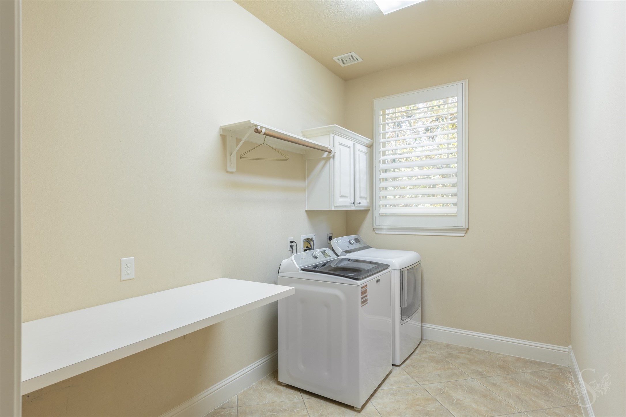 5803 Mustang Ridge Lane Fulshear, TX 77441 - Photo 22 of 48 Spacious utility room offers upper cabinetry, hanging space and room for additional storage or organization. A window with plantation shutters brings in natural light, while the washer and dryer are included with the home.