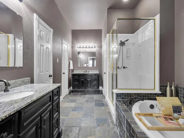 a bathroom with a granite countertop double vanity sink mirror and shower