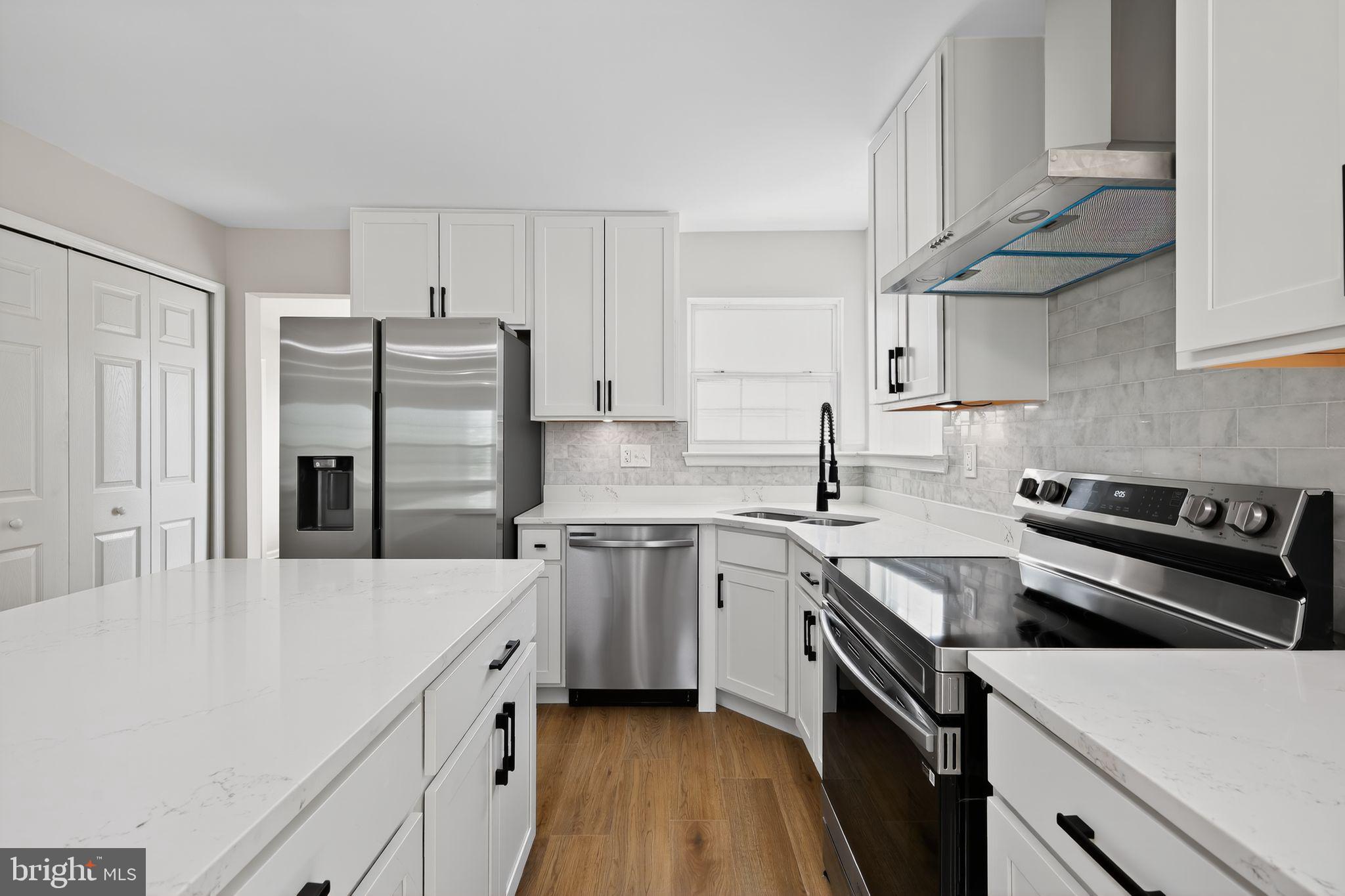 3003 Hillside Avenue Landover, MD 20785 - Photo 4 of 38 a kitchen with stainless steel appliances a sink dishwasher a refrigerator a stove and white cabinets with wooden floor