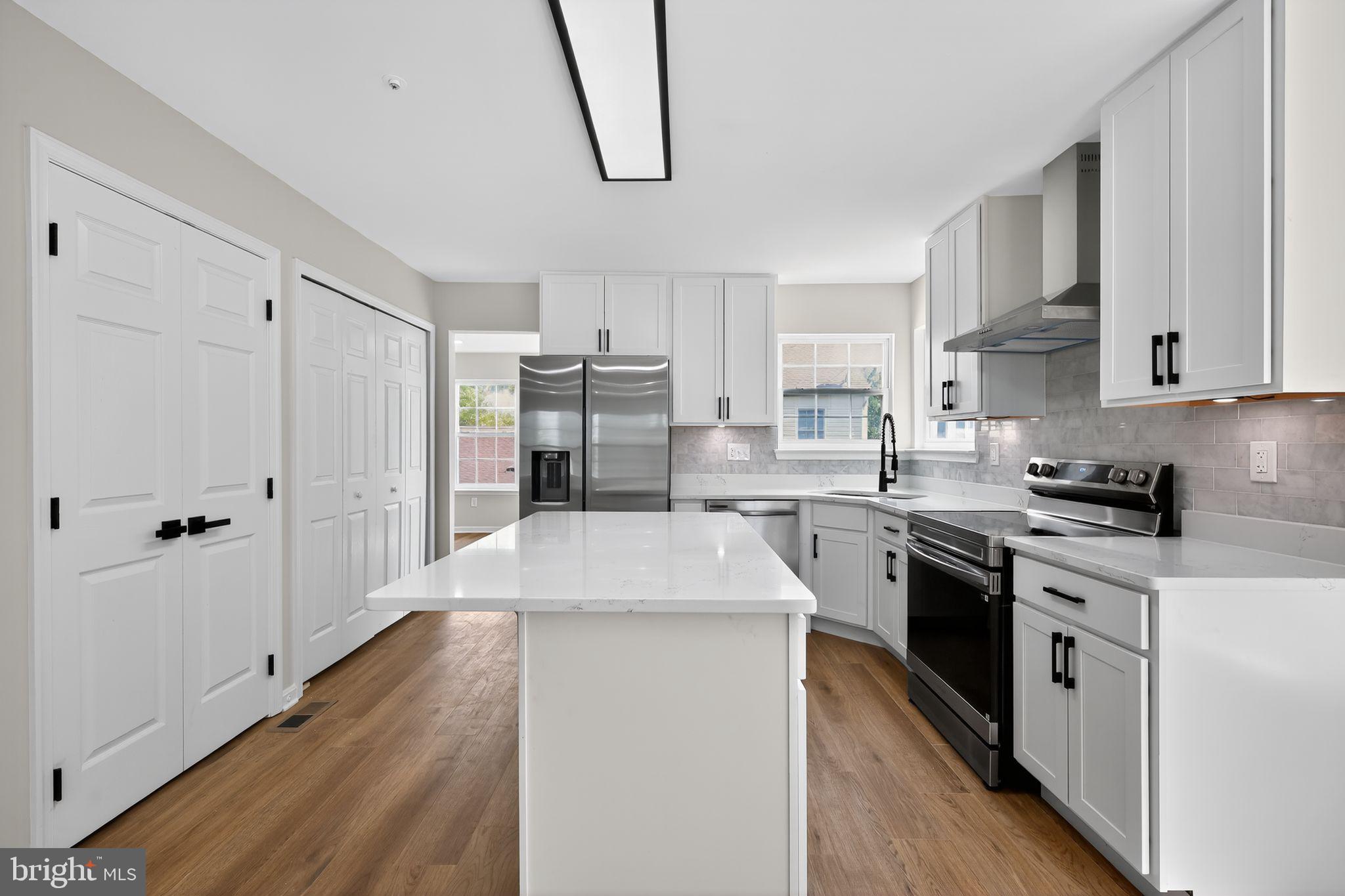 3003 Hillside Avenue Landover, MD 20785 - Photo 5 of 38 a kitchen with stainless steel appliances granite countertop a refrigerator a stove and white cabinets with wooden floor