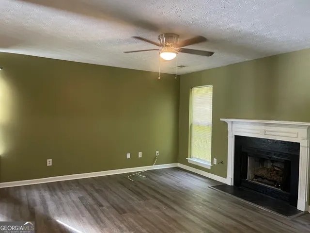 an empty room with wooden floor a fireplace and a ceiling fan