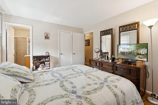 a bedroom with a large bed and a flat tv screen on dresser