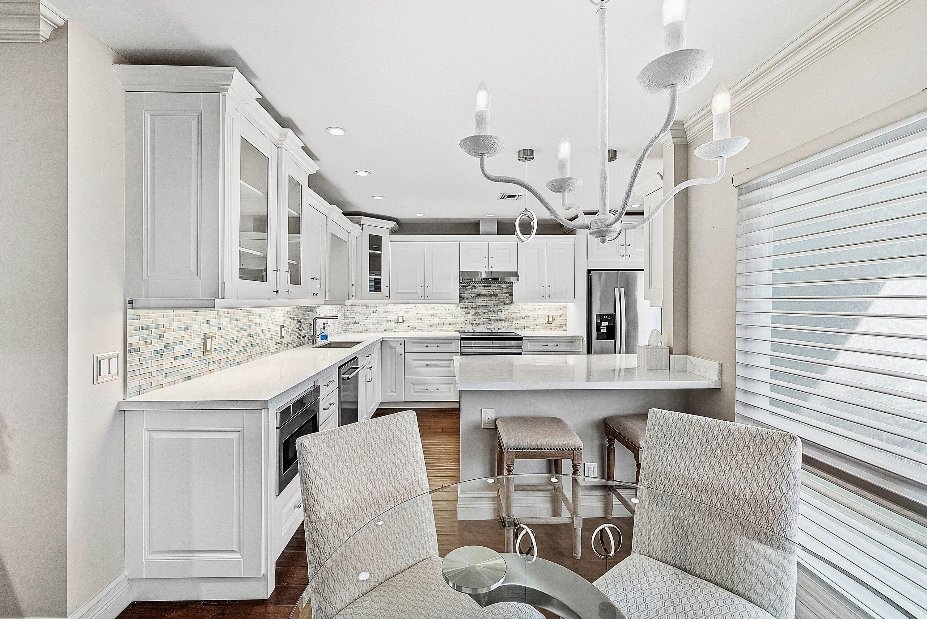 3675 Quail Ridge Drive, Unit BOBWHITE B Boynton Beach, FL 33436 - Photo 18 of 48 a kitchen with a sink dishwasher a stove a dining table and chairs with wooden floor