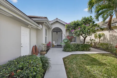 a view of a house with a small yard plants and palm trees