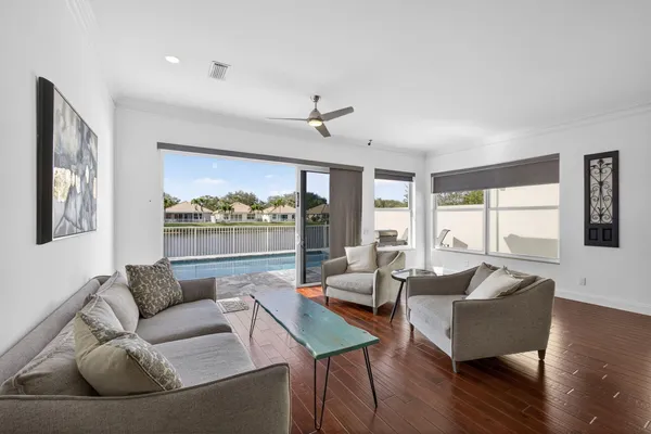 a living room with couches and kitchen view with wooden floor