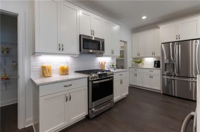 a kitchen with white cabinets and stainless steel appliances