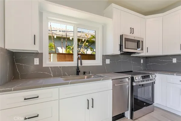 a kitchen with granite countertop white cabinets white stainless steel appliances and a sink