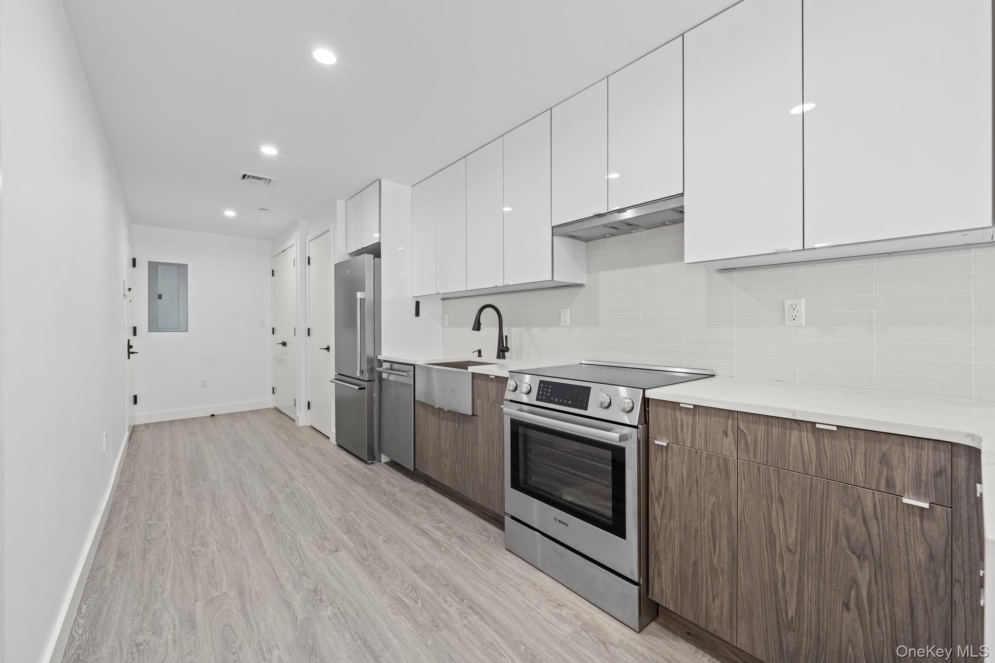 46-40 Vernon Boulevard, Unit 3B Queens, NY 11101 - Photo 5 of 17 Kitchen featuring white cabinetry, modern cabinets, stainless steel appliances, backsplash, and light wood finished floors