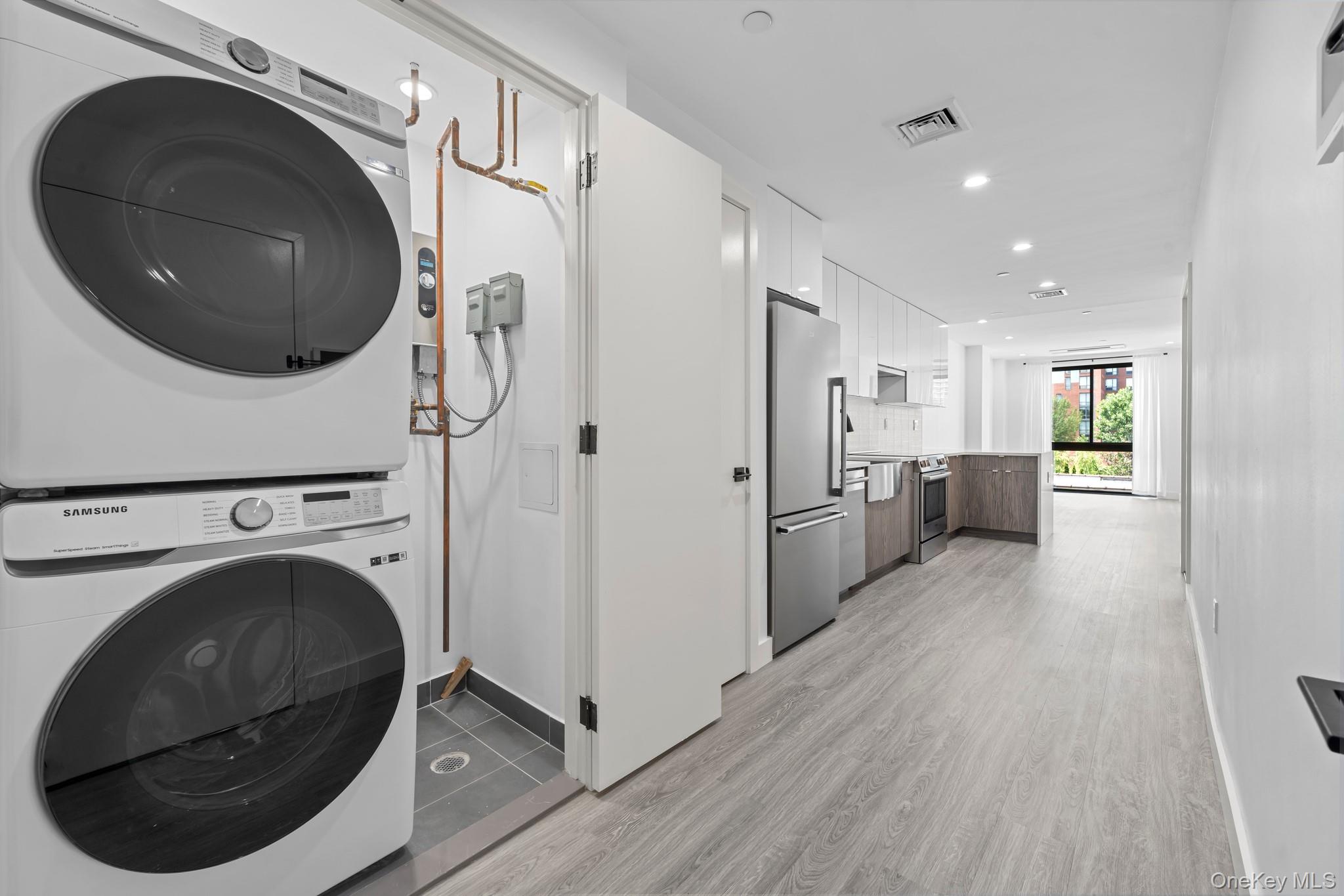 46-40 Vernon Boulevard, Unit 3B Queens, NY 11101 - Photo 8 of 17 Laundry area featuring light wood finished floors, stacked washer / dryer, and recessed lighting