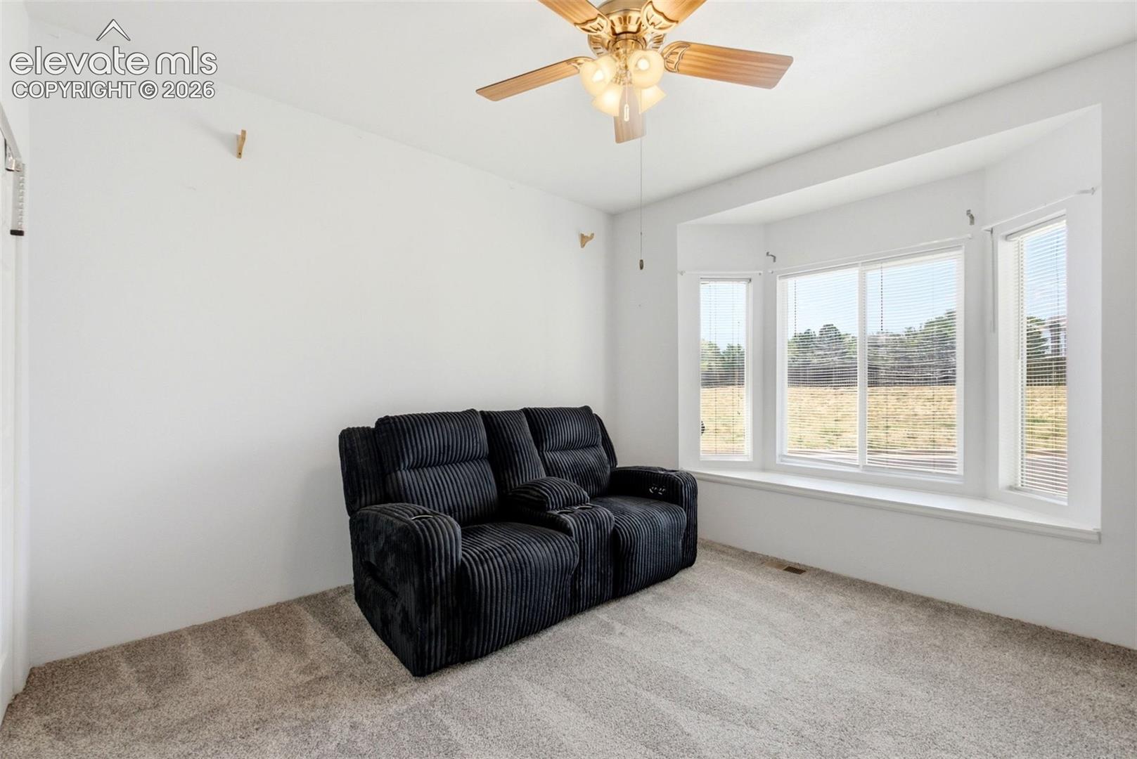 2002 Legacy Ridge View, Unit 107 Colorado Springs, CO 80910 - Photo 14 of 25 Bay window with multiple panels, ceiling fan with integrated lighting, and neutral carpeting