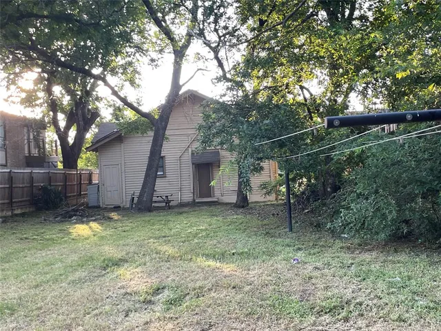 a backyard of a house with plants and large tree