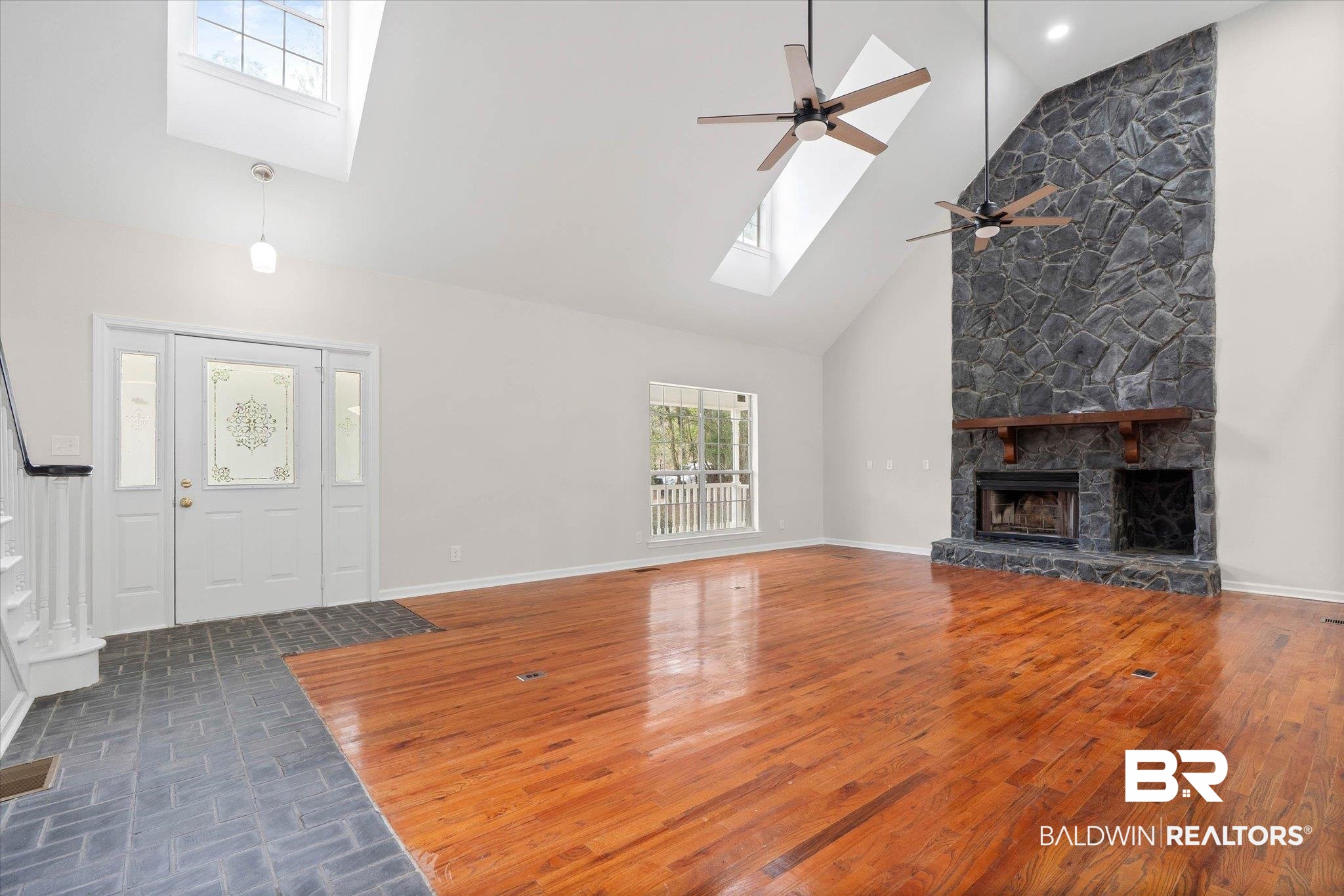 106 Melanie Loop Daphne, AL 36526 - Photo 6 of 45 Unfurnished living room with a skylight, lofted ceiling, a fireplace, dark wood finished floors, and a ceiling fan