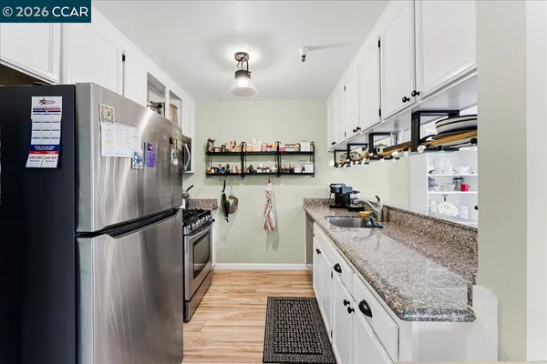 a kitchen with stainless steel appliances granite countertop a refrigerator a stove and a sink