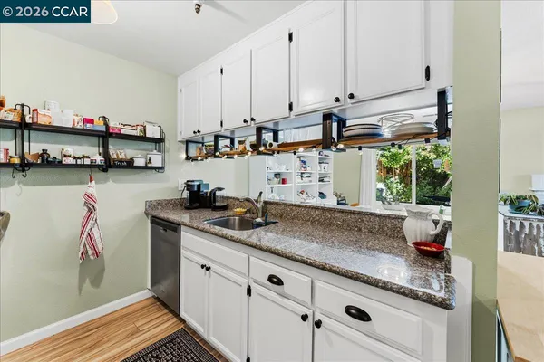 a kitchen with stainless steel appliances granite countertop a sink a stove and white cabinets