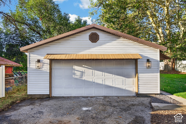 147 Center Street Clearfield, UT 84015 - Photo 5 of 55 Detached garage featuring white vinyl siding, a brown shingle roof, decorative metal awning, and exterior wall sconces