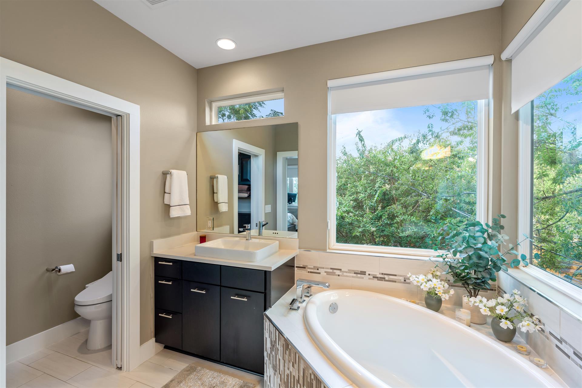 3806 Bull Creek Road, Unit B Austin, TX 78731 - Photo 25 of 37 Sunlight streams through large windows, illuminating the deep soaking tub and beautifully tiled floors, creating a bright and tranquil retreat.