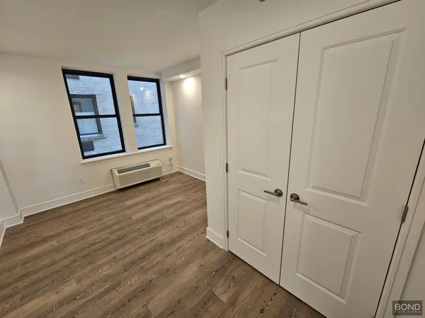 a view of a hallway with wooden floor and closet