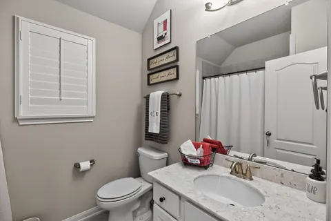 a bathroom with a granite countertop sink vanity mirror and toilet