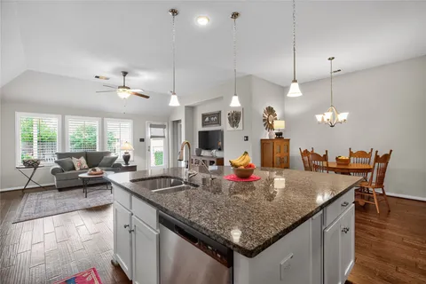 a kitchen with center island a sink dishwasher a dining table and chairs with wooden floor