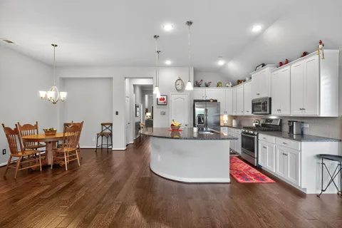 a kitchen with stainless steel appliances kitchen island granite countertop a dining table chairs and sink