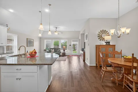 a view of a dining room and livingroom with furniture wooden floor a chandelier
