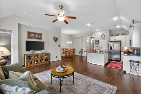 a living room with furniture kitchen view and a wooden floor