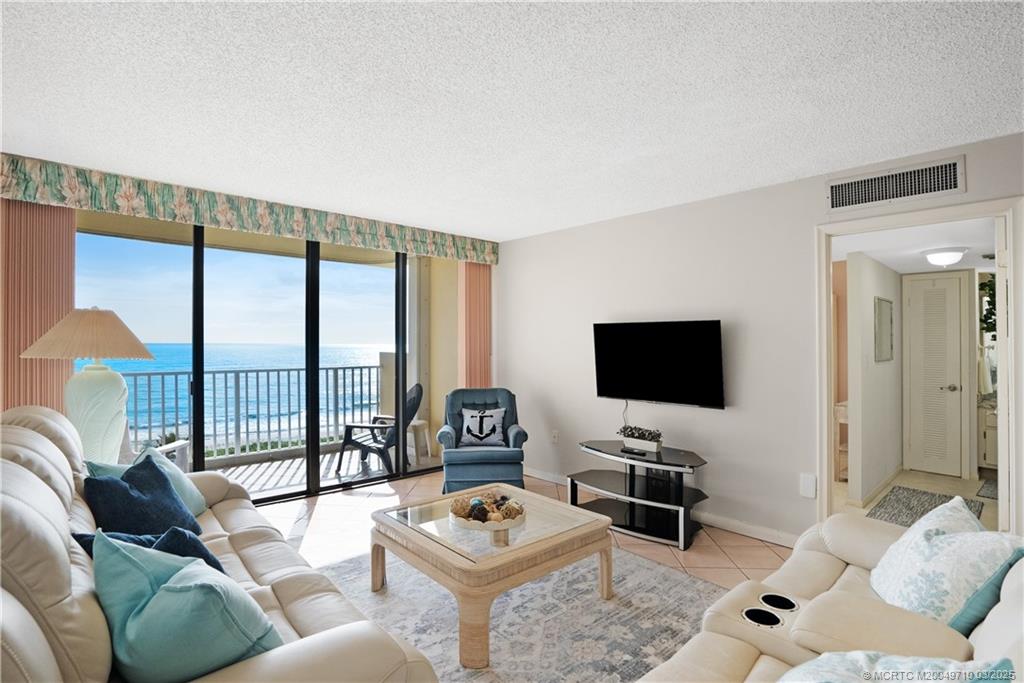 3200 North Hwy A1A, Unit 805 Fort Pierce, FL 34949 - Photo 19 of 43 a living room with furniture a flat screen tv and a floor to ceiling window