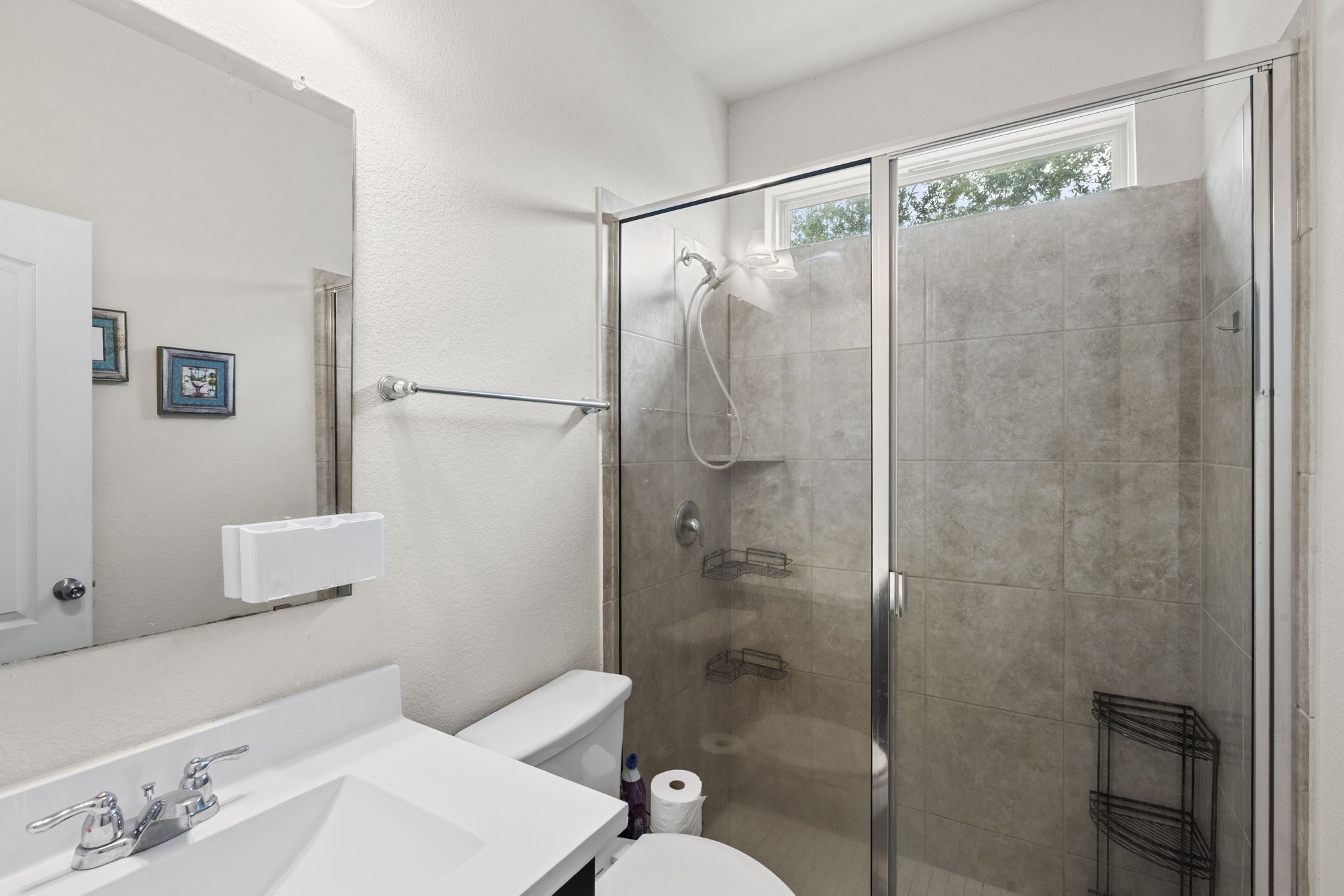 373 Rough Bark Street Buda, TX 78610 - Photo 16 of 39 A well-appointed full bathroom on the mail level features a spacious glass-enclosed shower and a pristine vanity.