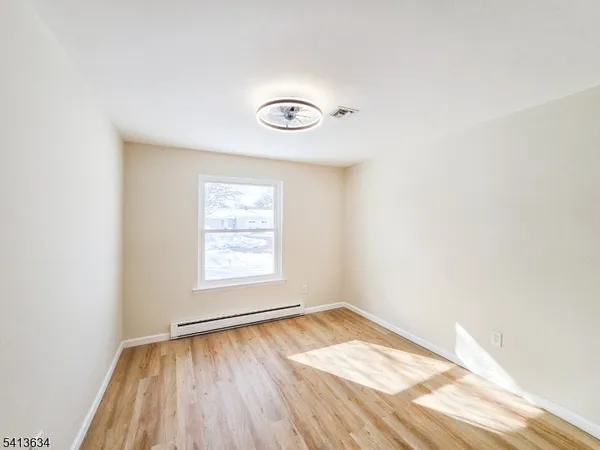 an empty room with a window and wooden floor
