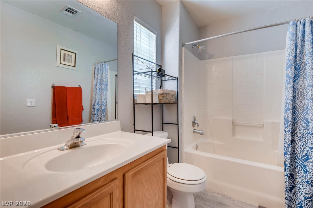 10451 Processor Court Las Vegas, NV 89129 - Photo 22 of 28 A compact bathroom offers a simple vanity, full mirror, and a combined shower-bathtub unit for everyday convenience.