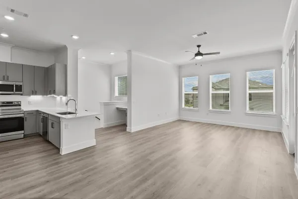 a large white kitchen with stainless steel appliances granite countertop a stove top oven a sink and dishwasher with wooden floor