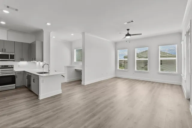 a large white kitchen with stainless steel appliances granite countertop a stove top oven a sink and dishwasher with wooden floor