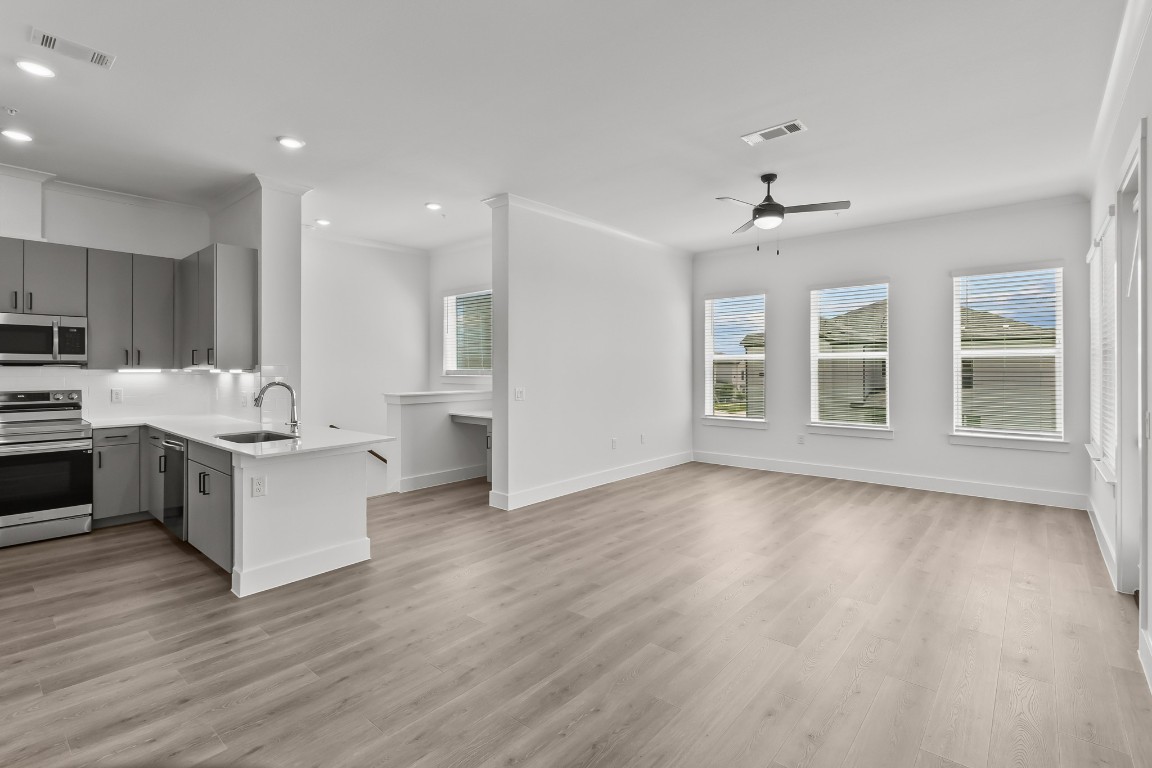 a large white kitchen with stainless steel appliances granite countertop a stove top oven a sink and dishwasher with wooden floor