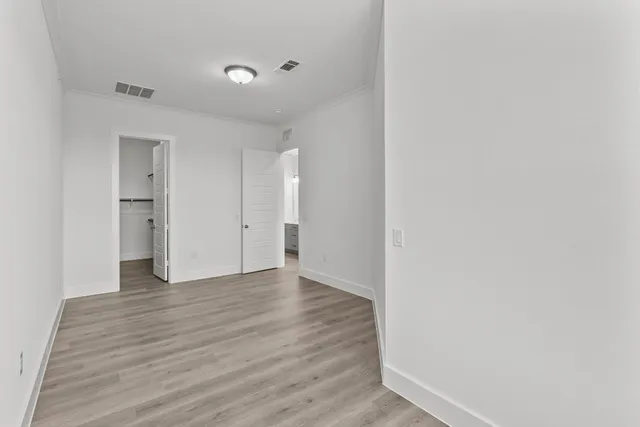 a view of an empty room with wooden floor and closet