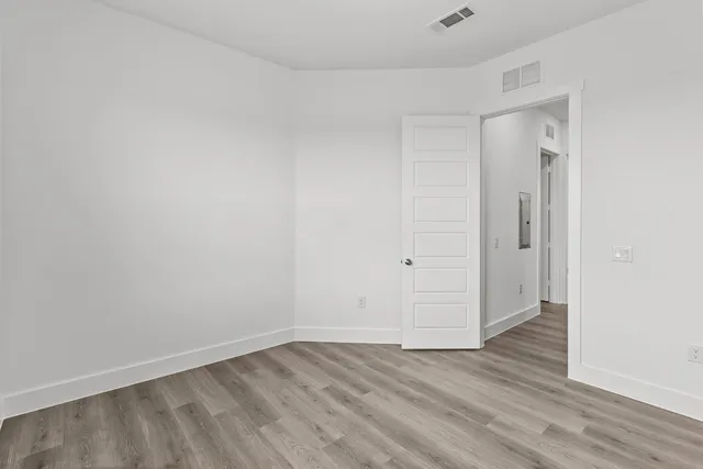 a view of an empty room with wooden floor and closet