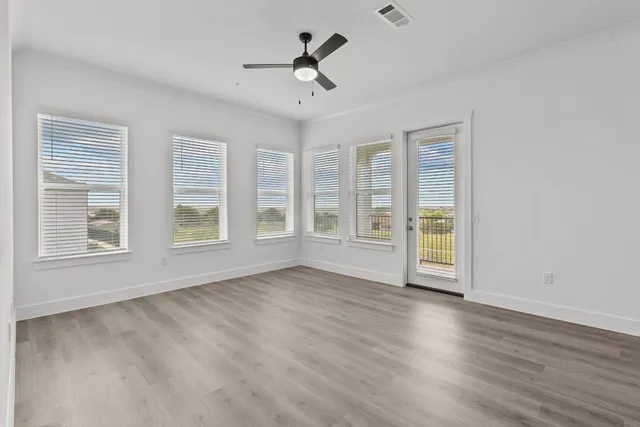 a view of an empty room with a window and wooden floor