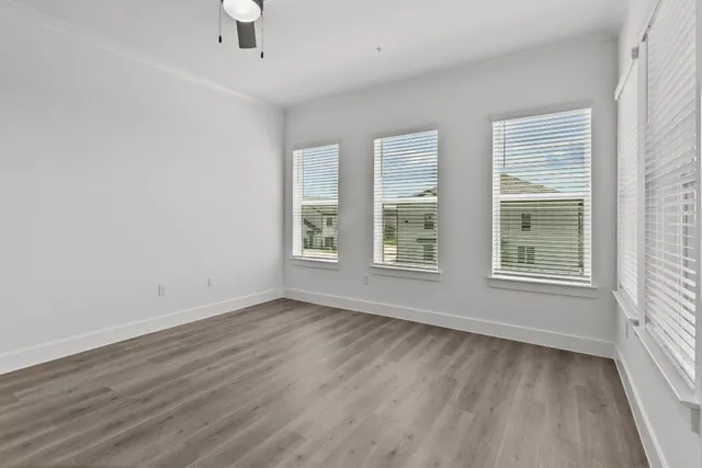 an empty room with wooden floor and windows