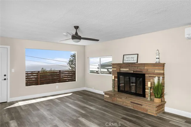 a view of an empty room with wooden floor fireplace and a window