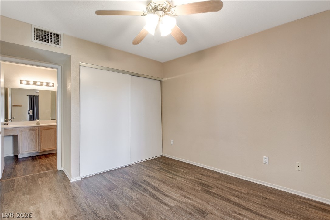 8070 West Russell Road, Unit 1064 Las Vegas, NV 89113 - Photo 19 of 35 Unfurnished bedroom with dark wood-type flooring, a ceiling fan, connected bathroom, and a closet