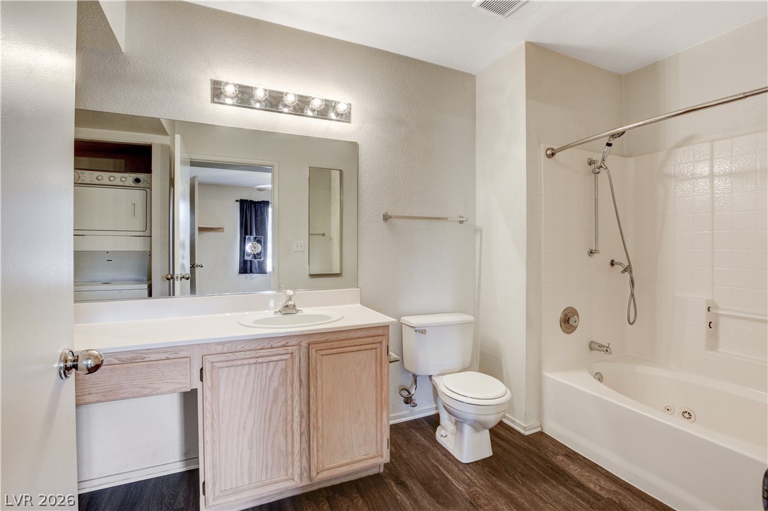 8070 West Russell Road, Unit 1064 Las Vegas, NV 89113 - Photo 20 of 35 Full bathroom featuring vanity, tub / shower combination, dark wood-type flooring, stacked washer / dryer, and a textured wall