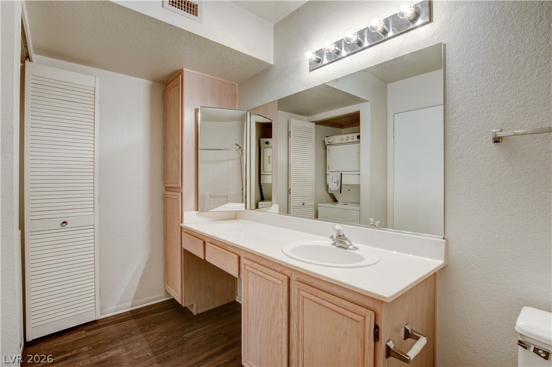 8070 West Russell Road, Unit 1064 Las Vegas, NV 89113 - Photo 21 of 35 Full bathroom featuring a textured wall, a closet, vanity, stacked washer and clothes dryer, and dark wood-style floors