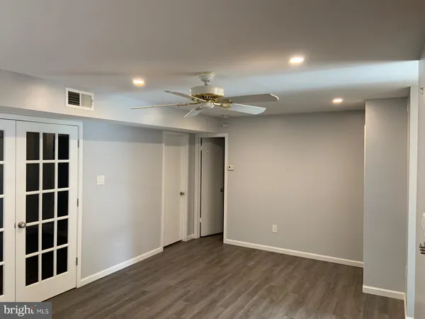 an empty room with wooden floor closet and windows