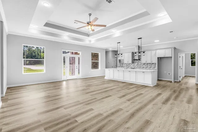 a view of an empty room with kitchen and window