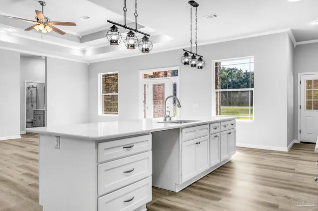 a large kitchen with granite countertop a stove a sink dishwasher a dining table and chairs with wooden floor