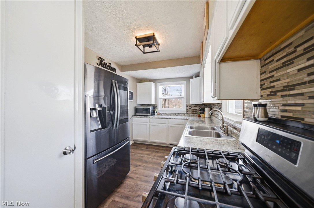 3905 Kent Road Stow, OH 44224 - Photo 20 of 45 Kitchen with stainless steel appliances, white cabinets, dark wood finished floors, a textured ceiling, and backsplash