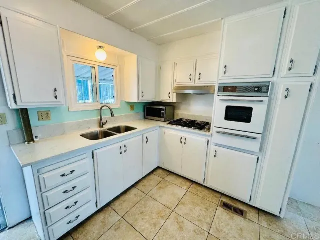 a kitchen with cabinets appliances a sink and a window