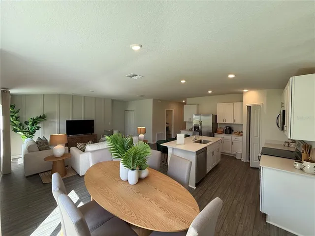 a living room with furniture kitchen view and a potted plant