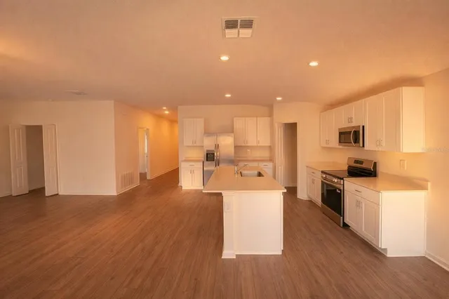 a view of a kitchen with kitchen island a sink wooden floor and a refrigerator