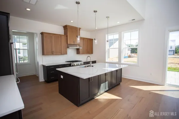 a kitchen with granite countertop a refrigerator a stove a sink dishwasher and wooden cabinets